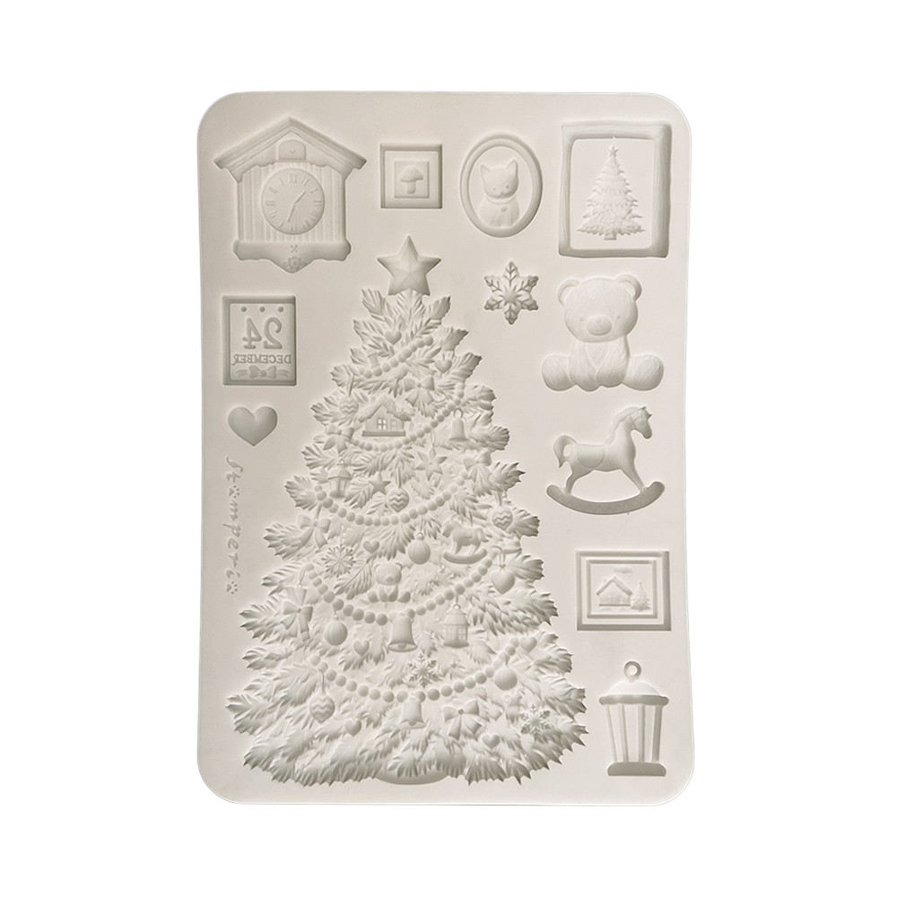 A rectangular silicone mold with Christmas-themed embossed designs, including a large decorated Christmas tree, a teddy bear, a rocking horse, a cuckoo clock, snowflakes, and small framed illustrations.