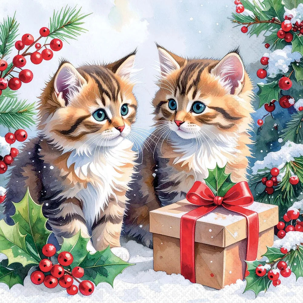 Two kittens with a gift box surrounded by holly leaves and berries on a snowy background