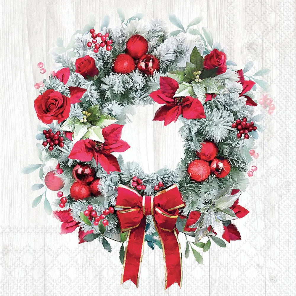 Decorative Christmas wreath with red flowers, berries, and a bow on a white background