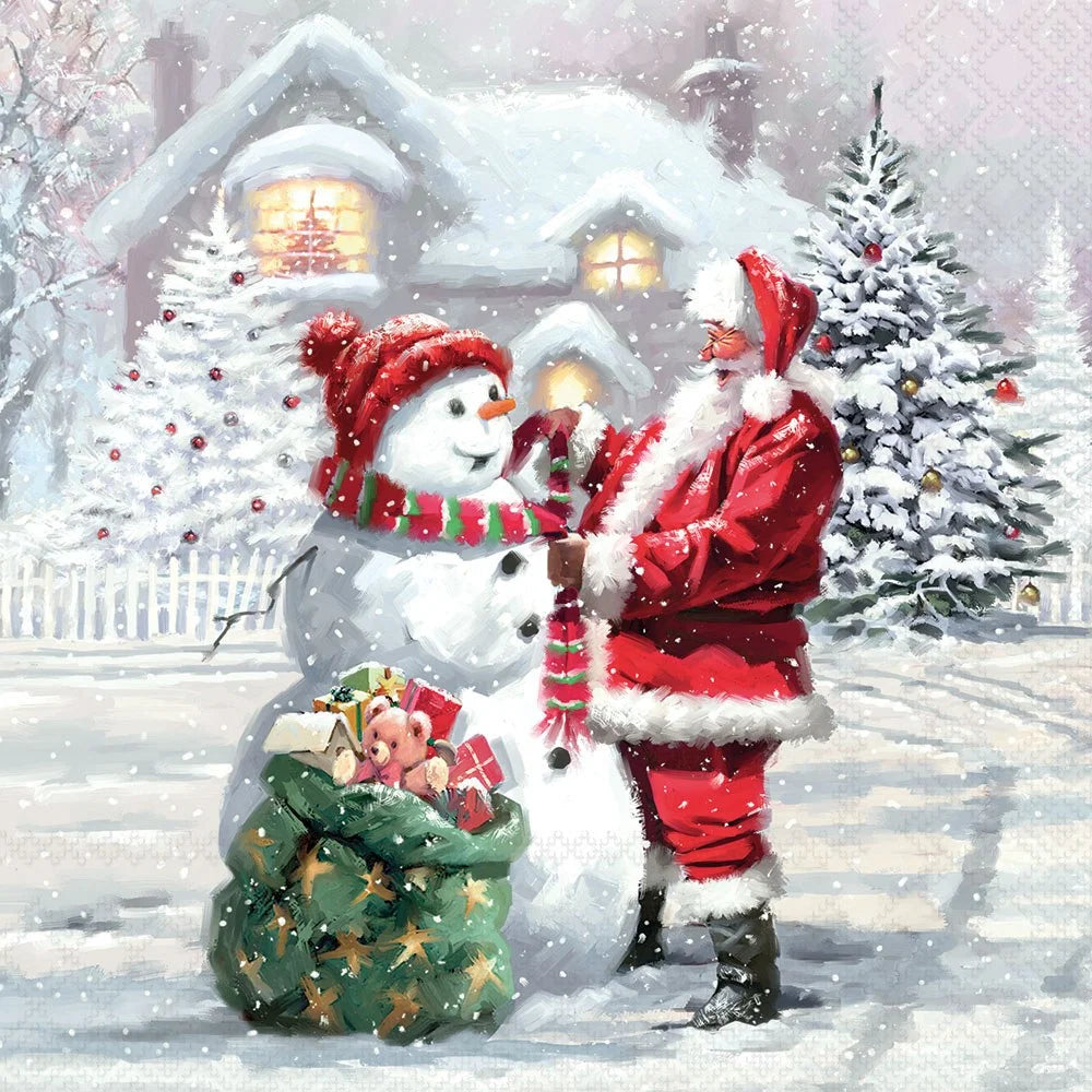 A festive winter scene showing Santa Claus in a red suit with white fur trim standing beside a snowman wearing a red hat and striped scarf. A green sack filled with wrapped gifts sits at the snowman's feet, and snow-covered trees and a house with glowing windows appear in the background during a snowfall.