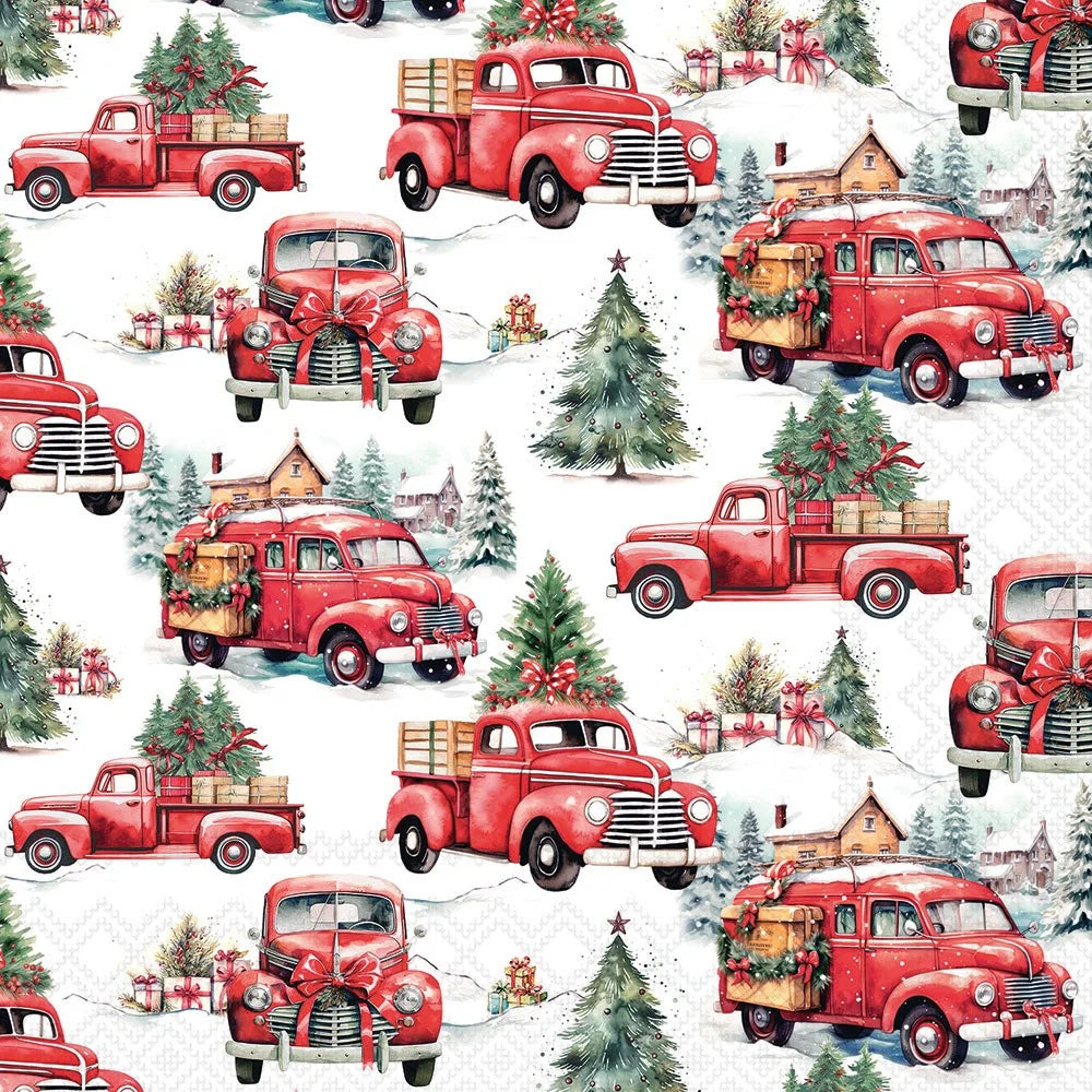 A repeating holiday-themed pattern featuring vintage red pickup trucks carrying Christmas trees and gifts, with snowy trees, houses, and wrapped presents on a white background.