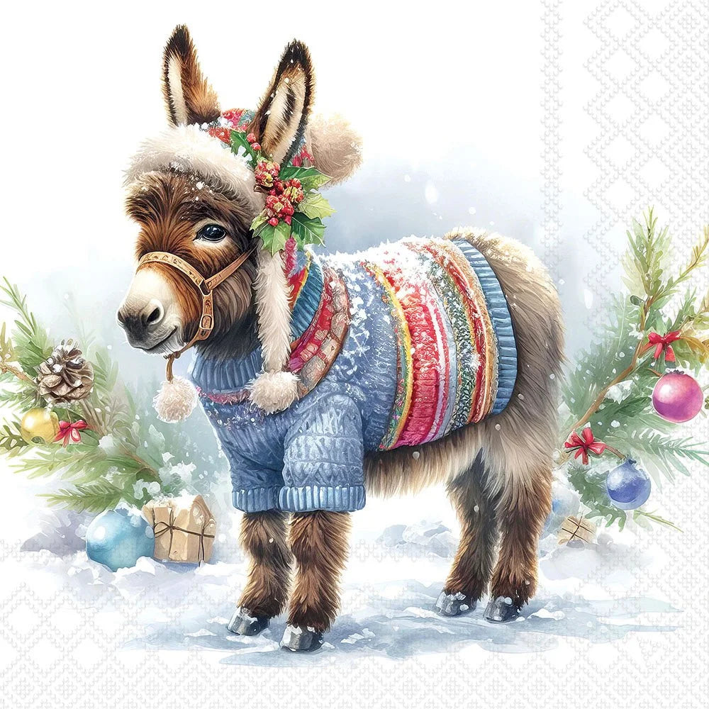 A festive illustration of a donkey wearing a blue knit sweater, a white faux-fur hat with pom-poms, and a green holly wreath, standing in snow with Christmas trees and ornaments around it.